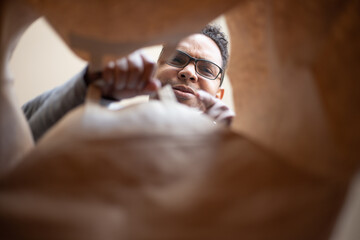 Obraz premium latin man opening box at home due to pandemic
