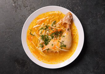 noodle soup with chicken leg and herbs on a dark