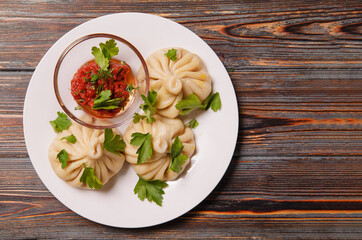 khinkali with tomato sauce, herbs on a dark wooden , top view, dumplings