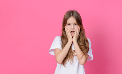 girl 10 years old in a white top holding her head and surprised on a pink background, emotions, child