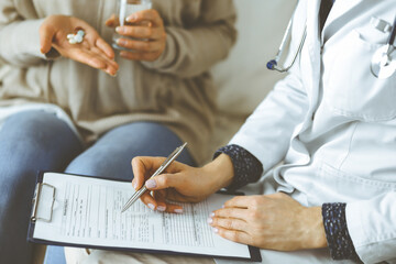 Fototapeta premium Unknown woman-doctor and patient discussing current health examination while sitting indoors. Stay at home concept during Coronavirus pandemic and self isolation quarantine