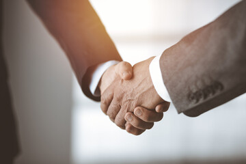 Business people standing and shaking hands in sunny office, close-up. Handshake and marketing