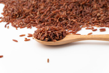 Red rice (brown rice)  in a wooden spoon isolated on a white background, Red rice are scattered on the ground. copy space.