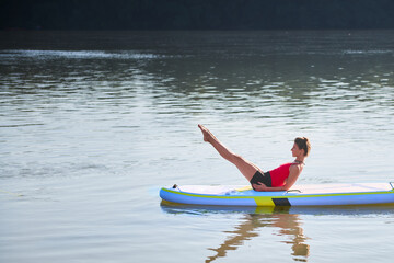 Woman practising yoga during morning hours on a paddleboard