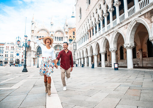Fototapeta Couple of tourists visiting Venice, Italy - Boyfriend and girlfriend in love running together on city street at sunset - People, love and holidays concept  