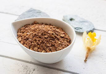 Closeup of a cup of cereal oat meal on a white wooden top with stones and flower decoration setup