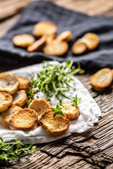 Small round mini bake rolls with lovely crunchy flavour and goldish colour made of baked bread and served in the paper or dish cloth with thyme