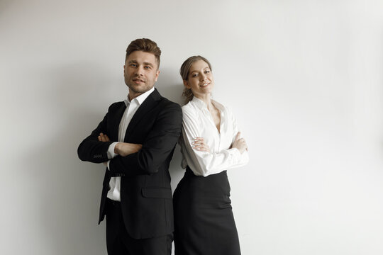 A man and a woman standing back to back on a white background. Business portrait of a couple in a business style.