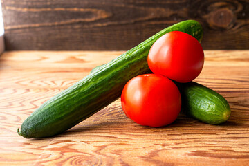 two cucumbers and two tomatoes on a wooden background