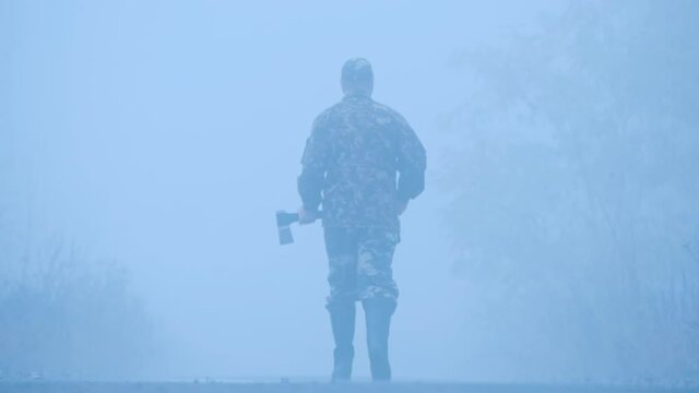 A man with an axe walks down the road in the fog - a terrible scene