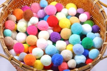 Colorful pompom in a wicker container on a white background