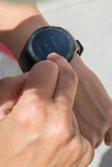 Fototapeta premium Unrecognizable Sportswoman Checking Smart Watch. Female Athlete Using Smart Watch On Wrist During Fitness Training On Street. 