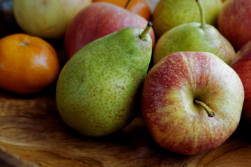 Close up of apples, pears and a tangerine in a fruit bowl