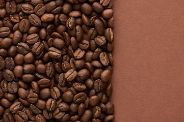Roasted coffee beans on brown background with copy space. Close up top view.