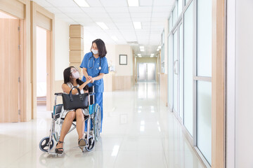 Asian patient on hospital wheelchair discussing with female doctor. Doctors are encouraging sick people during Covid 19.