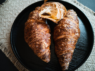 Croissants lie on a black tray close up
