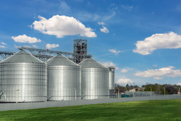 Scenic view of big modern steel agricultural grain granary silos cereal bin storage warehouse against blue sky. Agribusiness farmland rural industry silo landscape scene. Mill store farm facility © Kirill Gorlov