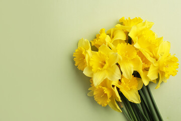 Beautiful daffodil bouquet on light green background, top view. Space for text