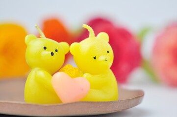 Beautiful doll-shaped candle against blurred flower background