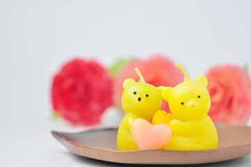 Beautiful doll-shaped candle against blurred flower background