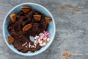 Mashed and fried spicy black beans with bread chips, onion and chili top view. Traditional Mexican cuisine frijoles refritos dish.