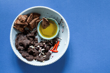 Mashed black beans with olive oil, bread chips, onion and chili top view with copy space. Mexican cuisine frijoles refritos meal.