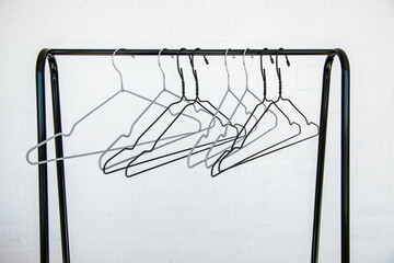 Stainless steel clothes rail with empty coathangers against a white wall