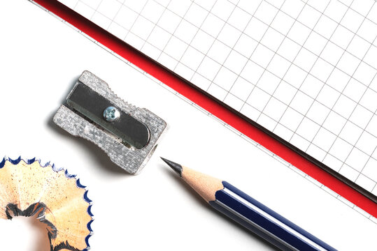 directly above close-up of pencil sharpener, pencil and notepad on white desk