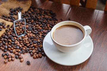 cup of coffee and coffee beans in a sack on  Brown background, top view