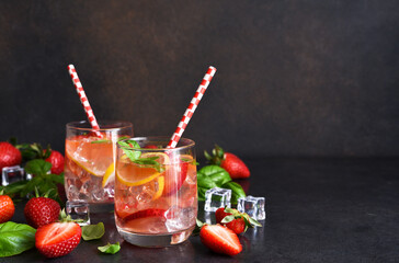 Summer drink. Cold lemonade with strawberries and basil on a concrete background.