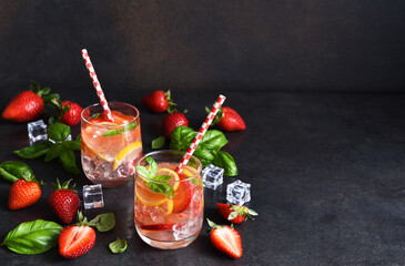 Summer drink. Cold lemonade with strawberries and basil on a concrete background.