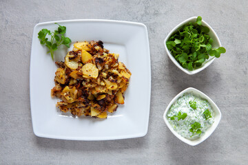 Fried potato dish with fresh microgreens: white mustard greens and watercress with yoghurt dip.
