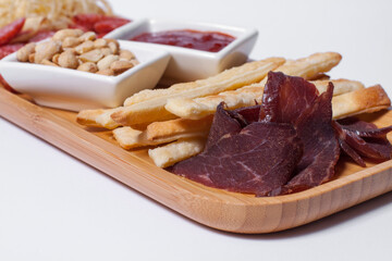 set of beer snacks with salami, peanuts, cheddar cheese and ketchup