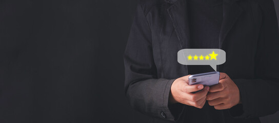 Customer service evaluation and satisfaction survey concepts. Customer hand hold smartphone and touching on screen with gold five star rating excellent feedback icon, Rated a very good review.