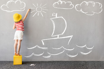 Happy kid draws a chalk ship on the wall - obrazy, fototapety, plakaty