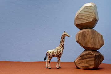 Giraffe plastic toy figure next to wooden stone blocks stacked.