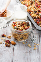 Homemade granola with fresh berries, honey, seeds  on white wooden background.