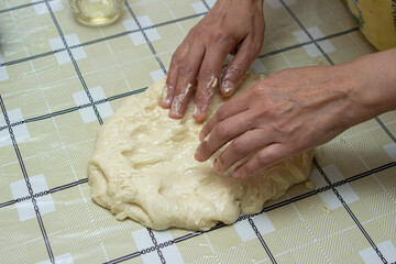 Female hands are working with dough. Homemade dough on the kitchen table. Home cooking. Homemade baking.