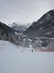 Fototapeta na wymiar Ski slope in gloomy weather, skiers, snowy landscape