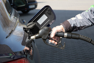 Male hand in uniform and in polyethylene glove preparing to refuel a car in the gas station. Refueling the car