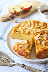 French cuisine. Invisible apple tart, almond petals dressing, red apples and cup of tea
