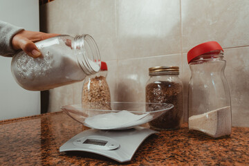 close-up of woman's hands using kitchen scale. Measuring sugar for cooking. Healthy and homemade food concept.