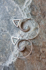 Silver metal decorative oriental spirale design earrings on natural neutral background