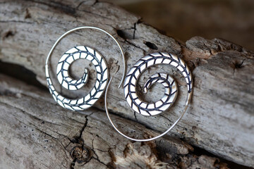Silver metal decorative oriental spirale design earrings on natural neutral background