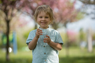 Beautiful blond child, boy, drinking water in the park on a hot day