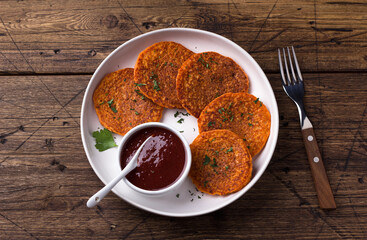 Lentil fritters with plum sauce, tkemali, greens in white plate on wooden table. Healthy vegan food