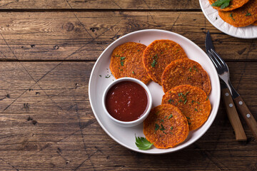 Lentil fritters with plum sauce, tkemali, greens in white plate on wooden table. Healthy vegan food