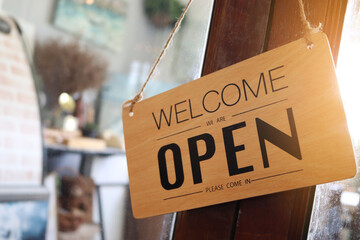 "Open" Wooden sign board hanging on door at entrance of cafe