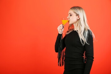 beautiful young woman holding a glass of cocktail isolated on colored background with copy space