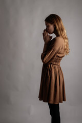 Fototapeta premium Woman in brown is having a heartache. Depression and sadness. Prayer.